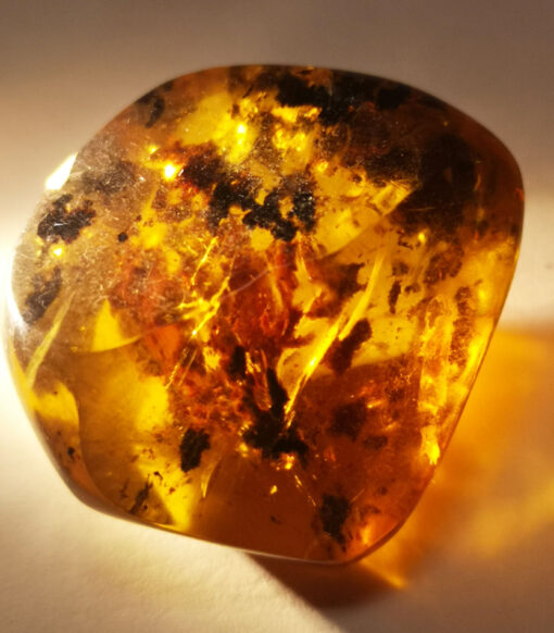 Irregularly shaped, and fiery yellow amber inclusion with several angular polished faces.