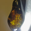 Dark and oblong shaped Myanmar amber pendant containing dense black foliage